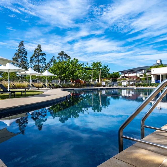 Outdoor pool with sun loungers and white parasols at Mercure Kooindah Waters