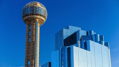 Reunion Tower with a glass building under a blue sky near Warwick Melrose Dallas