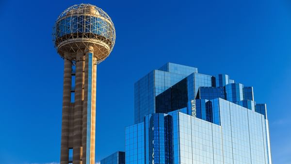 Reunion Tower and a tall glass building against a blue sky.