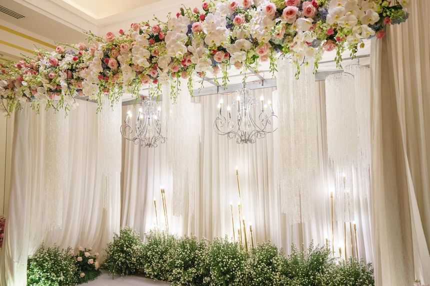 Elegant wedding backdrop adorned with lush floral arrangements, soft drapes and twinkling chandeliers at Park Hyatt Saigon