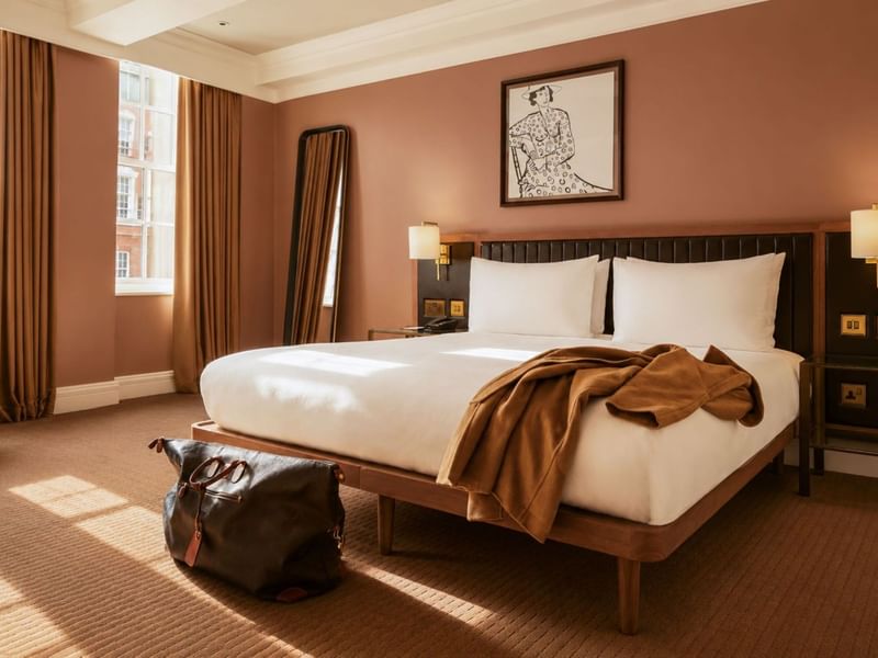 Sunlit Collection Premium Room with king bed, terracotta walls, floor mirror, and artwork at The May Fair Hotel, London.