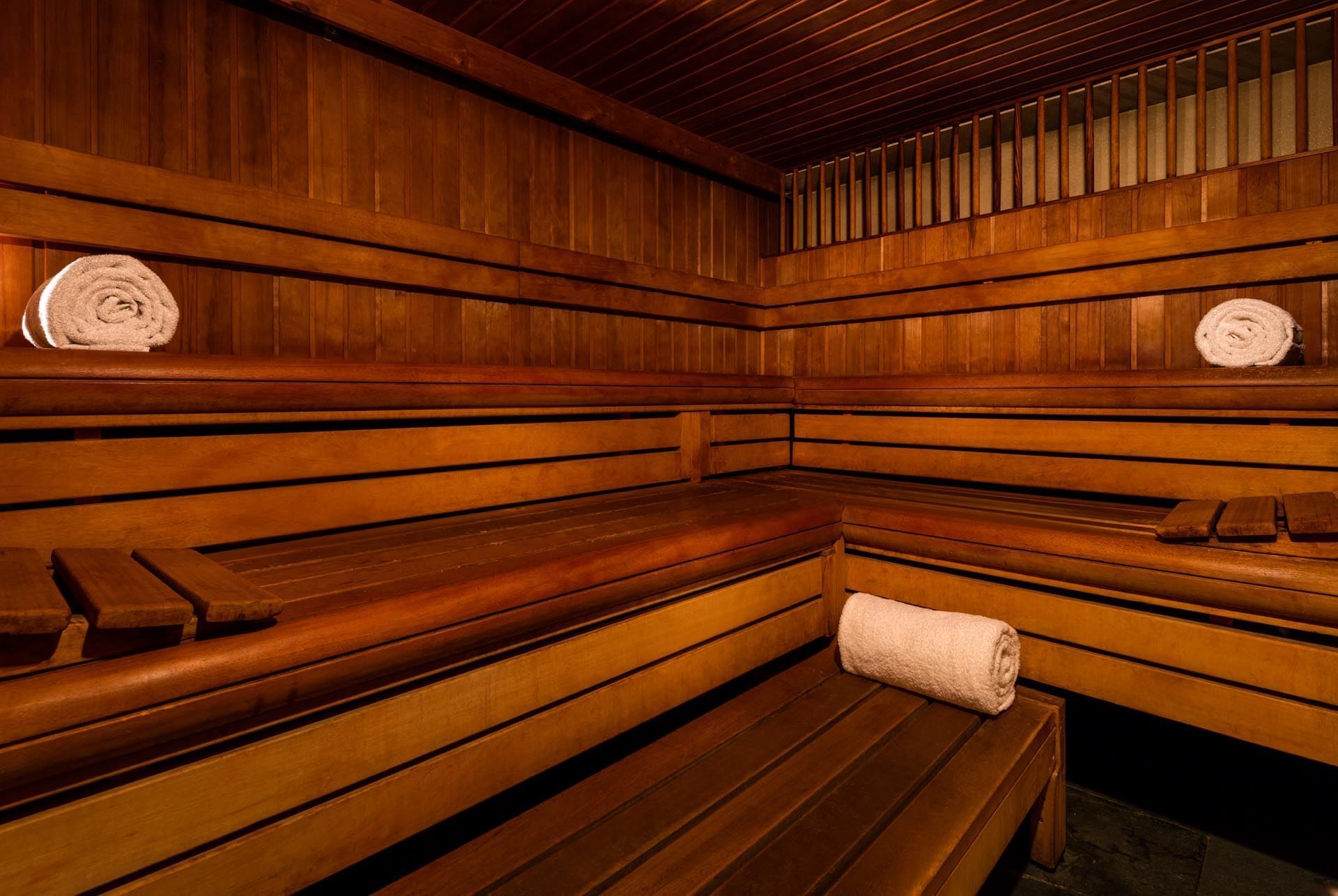 Steam room in May Fair Spa with polished wooden benches and rolled white towels at The May Fair Hotel