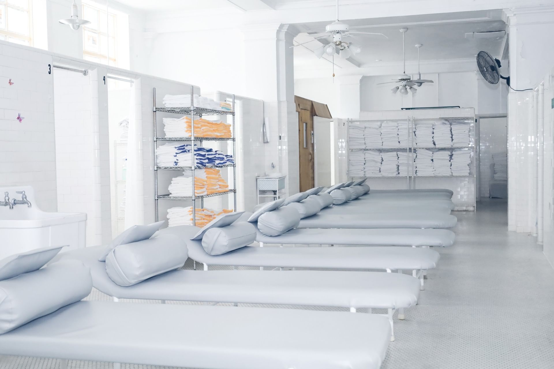 White padded loungers by a metal towel rack under a high white ceiling in a spa at Arlington Resort Hotel & Spa
