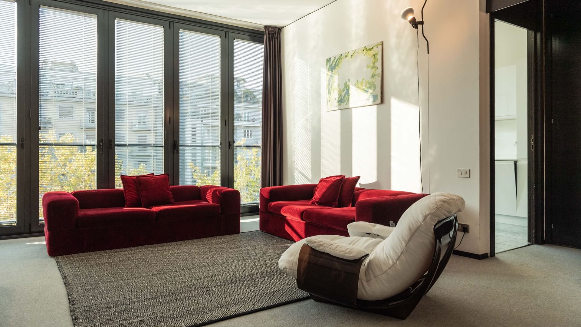 Suite con elegante soggiorno con divani rossi e vista finestra grande da DUPARC Contemporary Suites