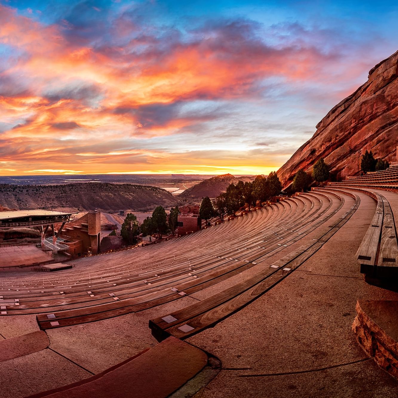 Red Rocks Amphitheatre with Stone benches by a rock formation under a vibrant sunset at an arena near Warwick Denver
