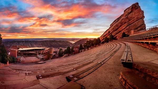 Red Rocks Amphitheatre with Stone benches by a rock formation under a vibrant sunset at an arena near Warwick Denver