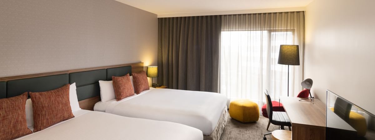 Superior Room with twin beds and a work desk by the window at Novotel Sydney International Airport