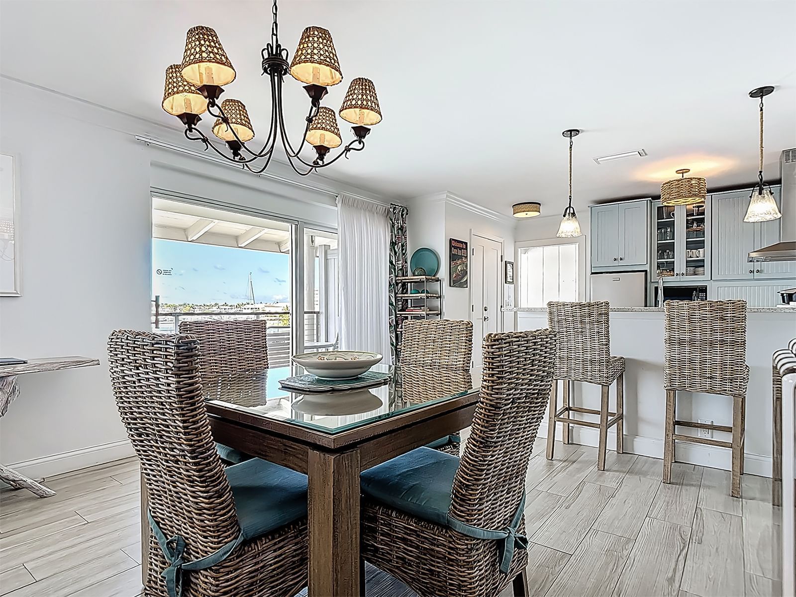Bayside Penthouse dining area with glass table and wicker chairs at Cove Inn at Naples Bay.