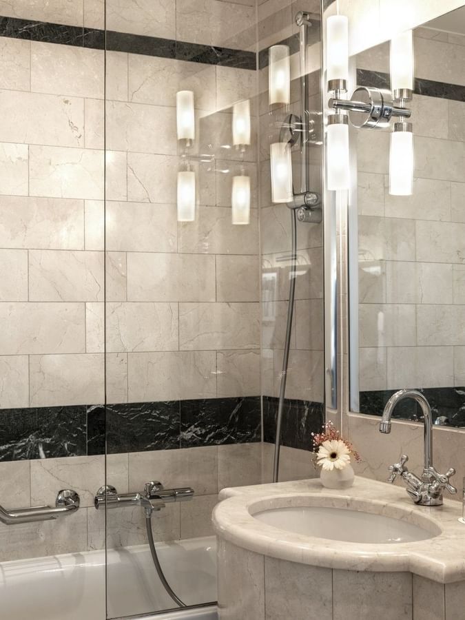 Penthouse Terrace Room with a vanity by a bathtub under modern glass light fixtures at Warwick Geneva