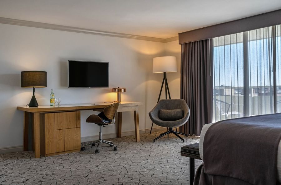 Modern desk with a swivel chair by a tall tripod lamp on a patterned carpet in Deluxe Rooms at Warwick Denver