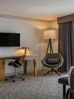 Work desk by a swivel chair under a wall-mounted TV in Deluxe Rooms at Warwick Denver