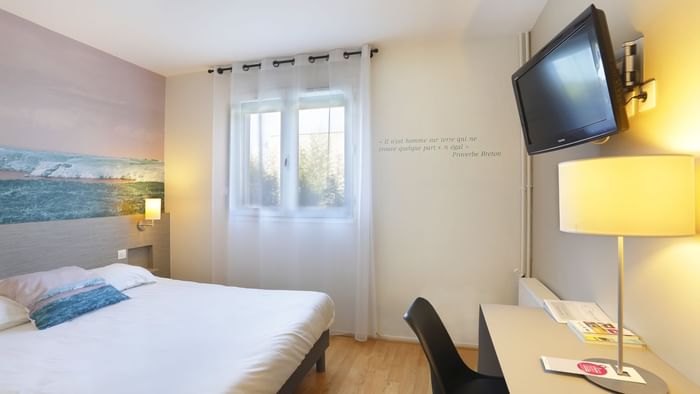 Interior of a room with a king bed & TV at Hotel Au Chene Vert