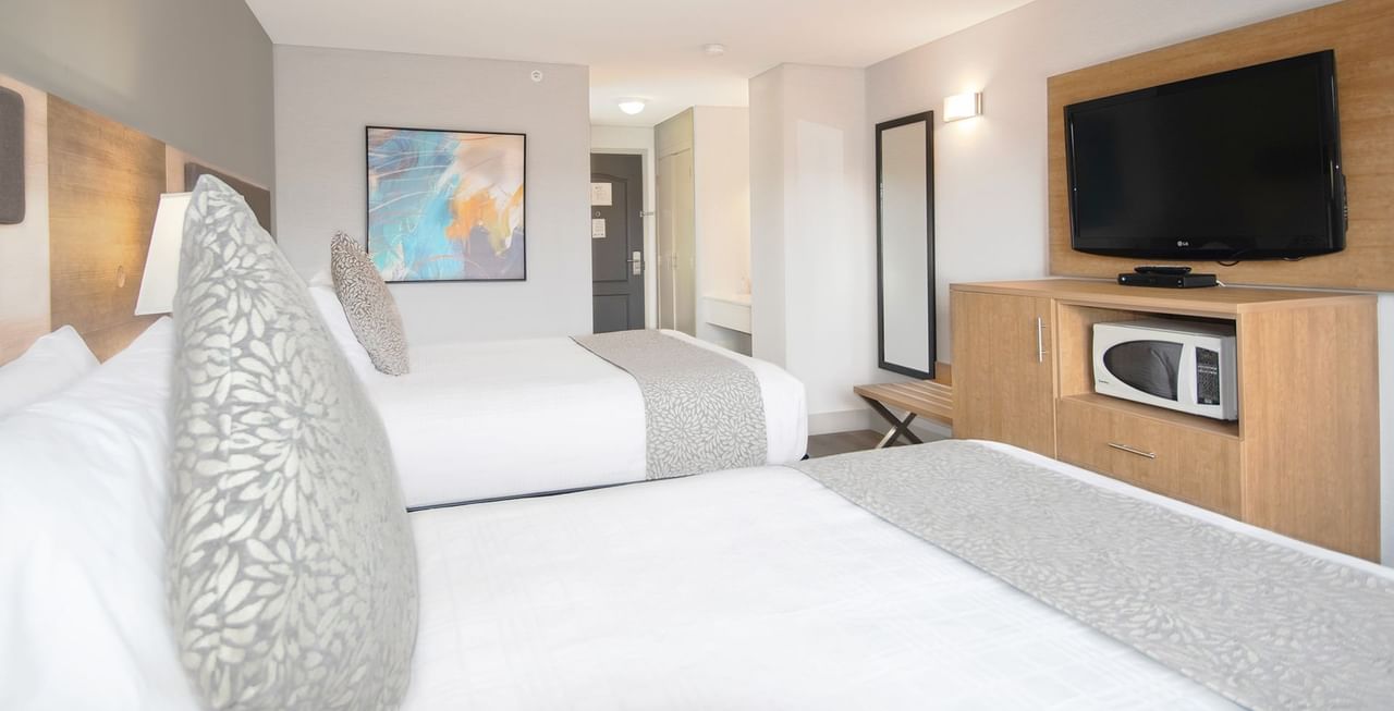 Hotel room with two queen beds, TV, microwave, mirror, and art on the wall