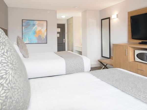 Hotel room with two queen beds, TV, microwave, mirror, and art on the wall
