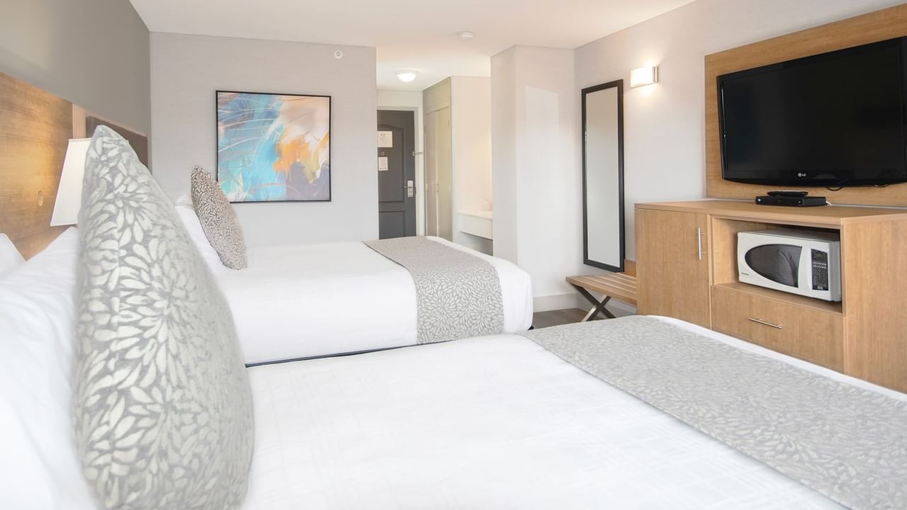 Hotel room with two queen beds, TV, microwave, mirror, and art on the wall