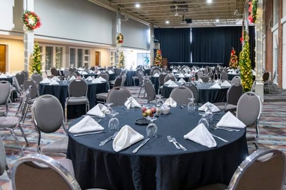 Round banquet tables set with white napkins and black cloths in a decorated event hall at Rodd Hotels & Resorts