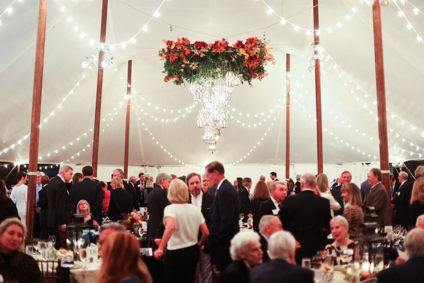 Guests gathering in a wedding venue with banquet tables, chandelier & floral decorations at The Clifton