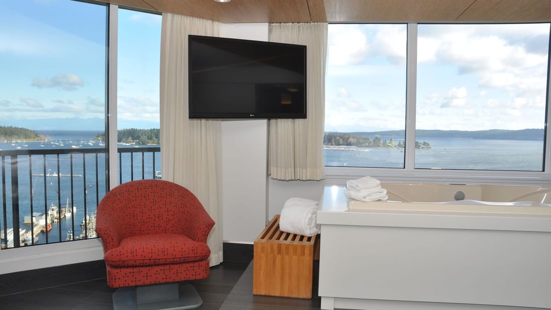 Sofa chair, tub and TV in hotel suite with ocean view