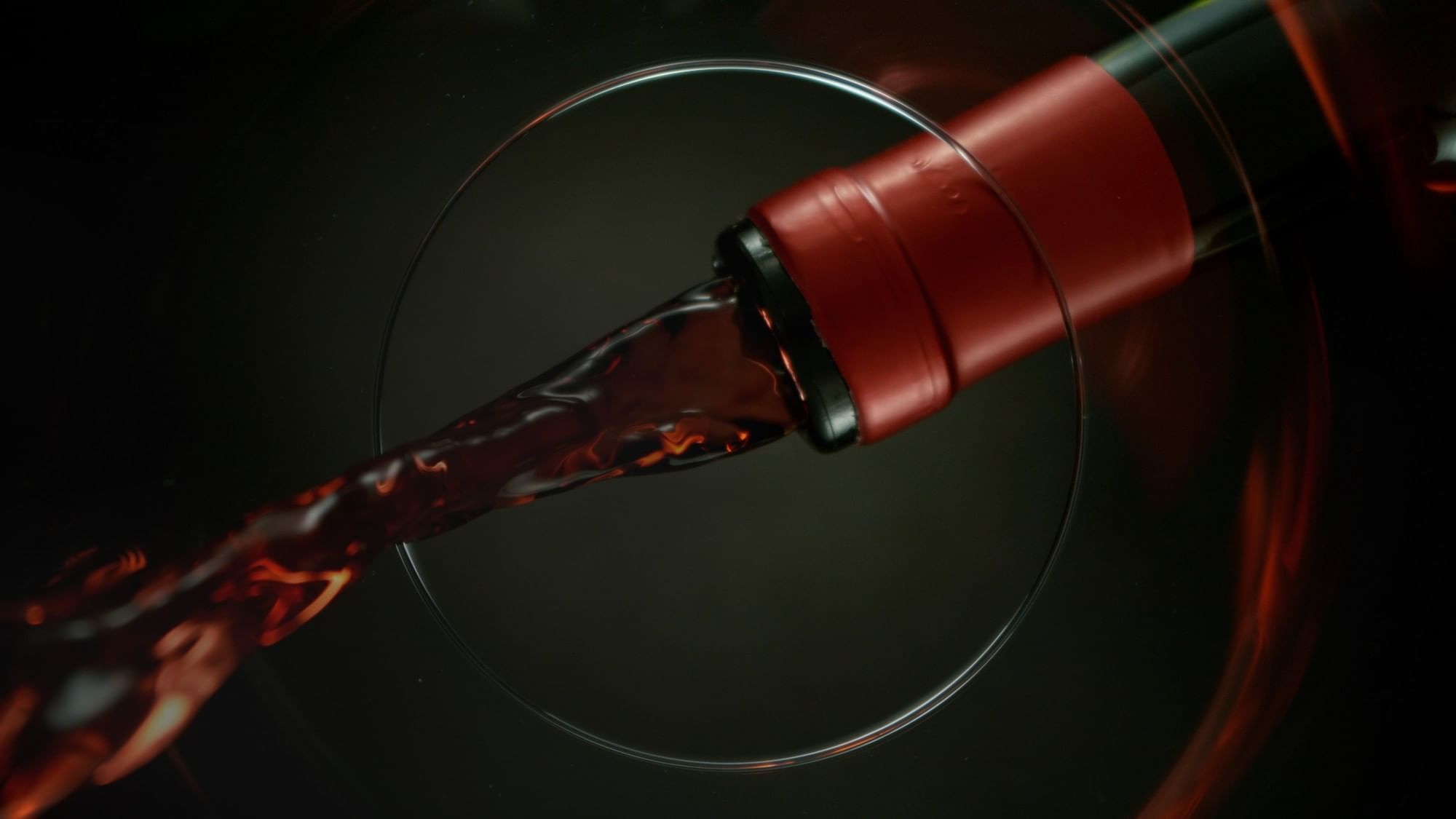 Close-up of red wine pouring from a bottle into a glass at Real Inn
