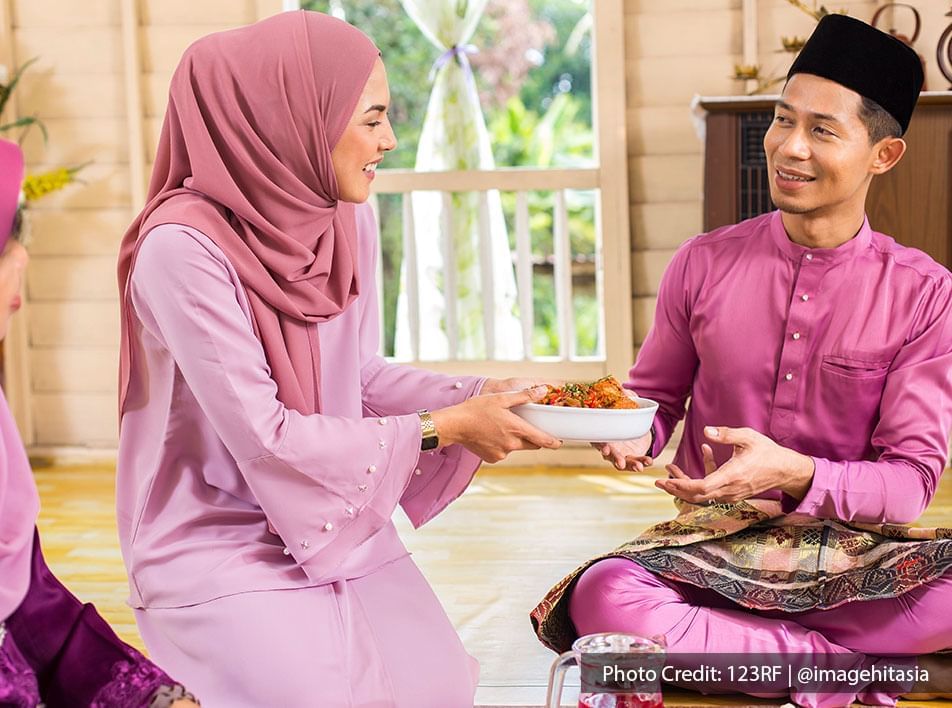 Muslim woman serving a bowl of chicken rendang to a man