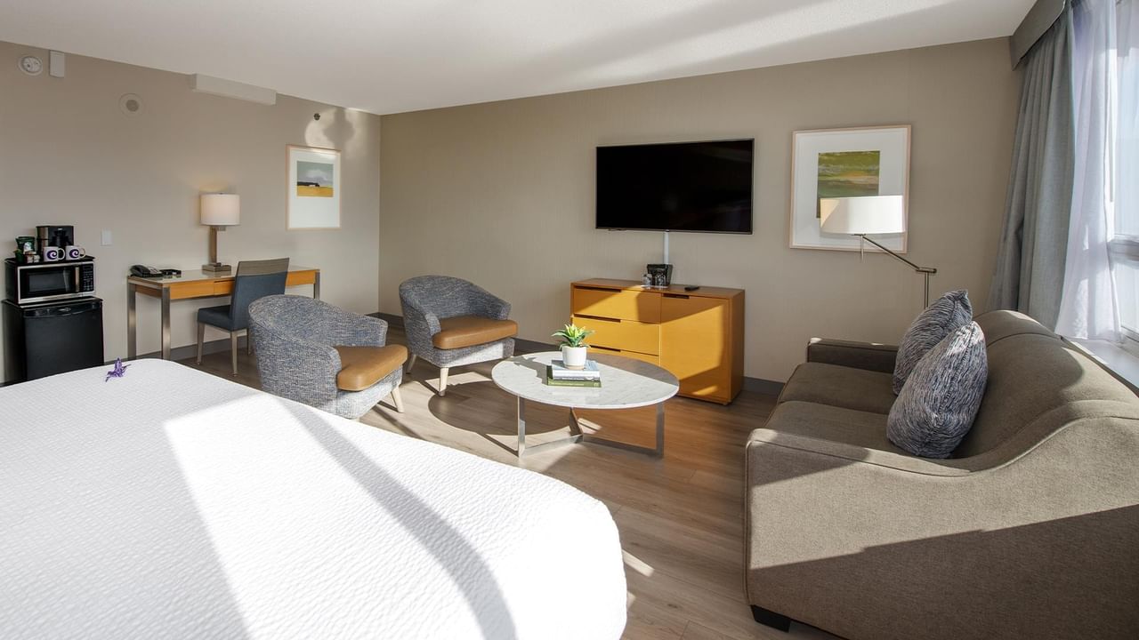Hotel room with couch, TV, and coffee table at Coast Chilliwack Hotel by APA.