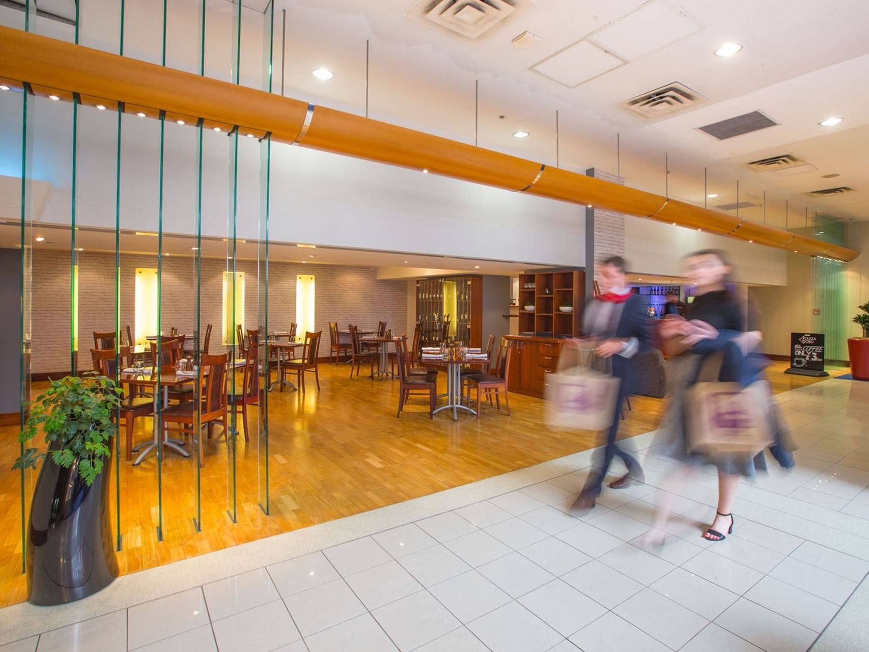 Guests passing by the dining & lounge area in the lobby at James Cook Grand Chancellor