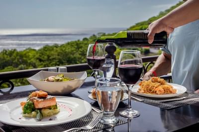 Variety of food dishes served with wine on a table in Bahía Restaurant at Villas Sol Beach Resort