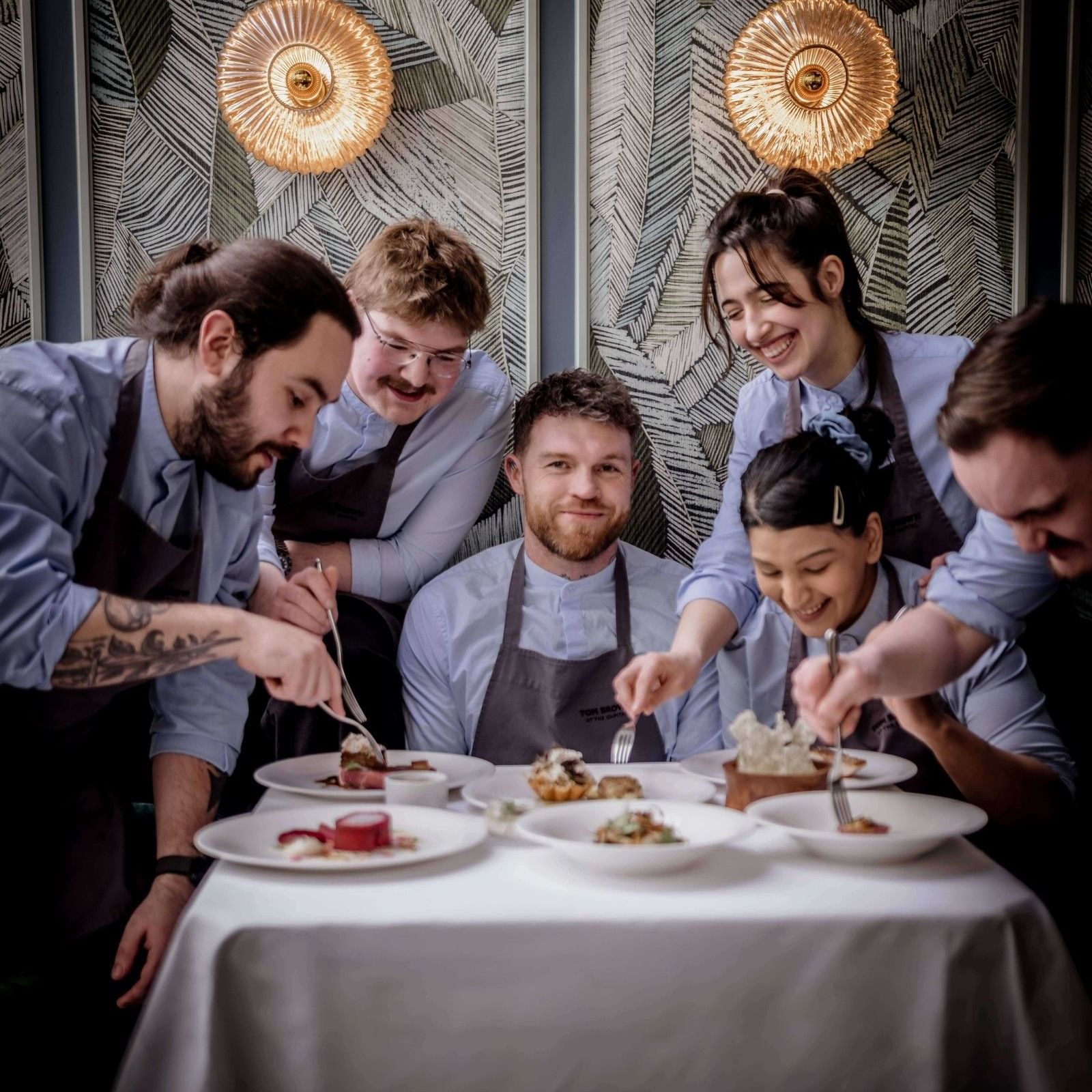 Tom Brown and team sharing a meal at a table, celebrating Michelin Star achievement.