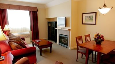 Elegant living area of The Suite featuring a couch, dining table and a TV at Pointe at Castle Hill