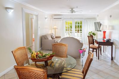 Bright and airy living space featuring a glass dining table with fruit in One Bedroom Croton Suite at Bay Gardens Hotel