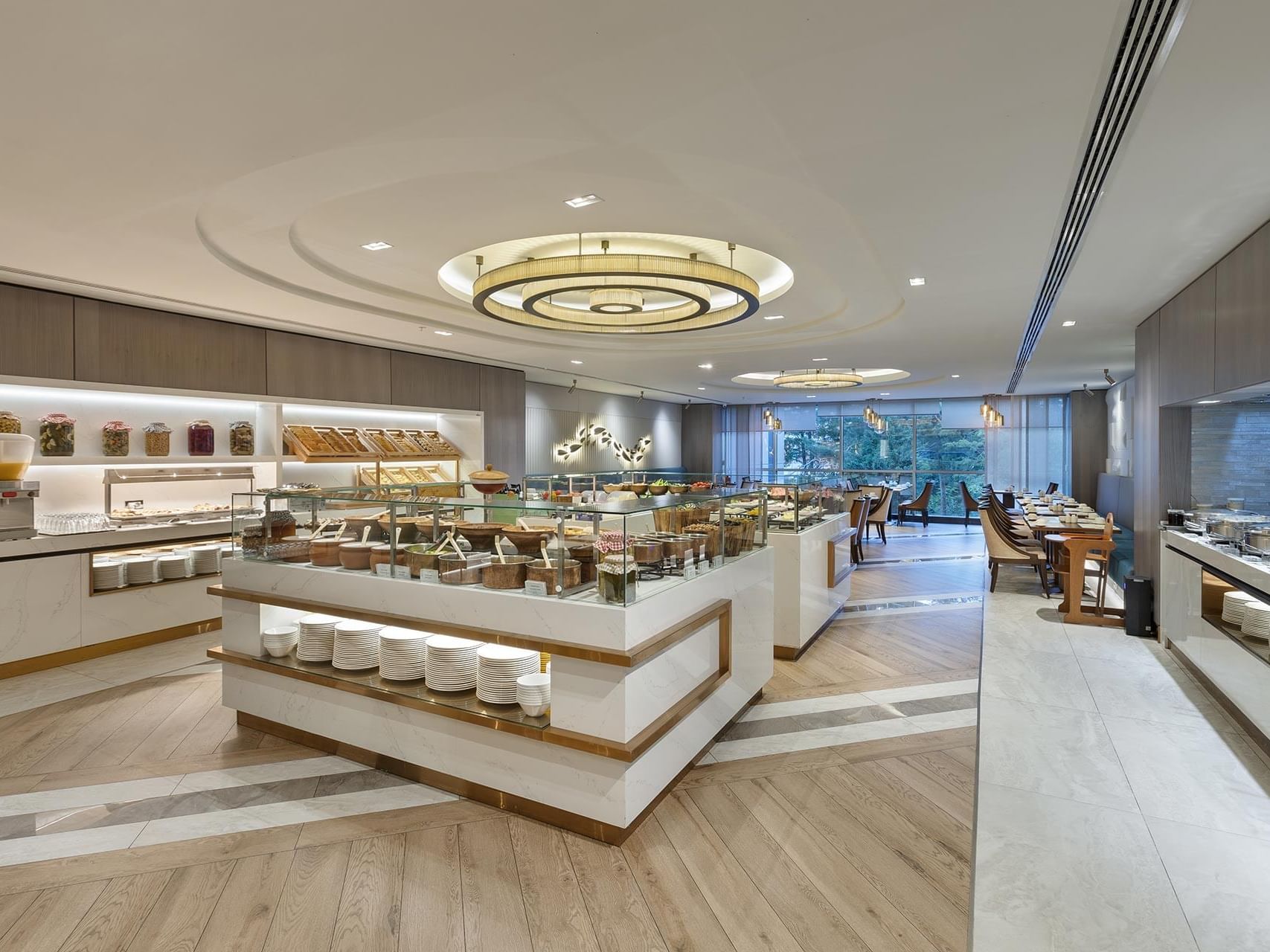 Tİtanic Port Bakırköy Alesta Restaurant’ta, cam vitrinlerle çevrili geniş açık büfe salonu, zarif tabak düzeni ve merkezdeki dairesel aydınlatma ile şıklığı ve konforu bir araya getiriyor.