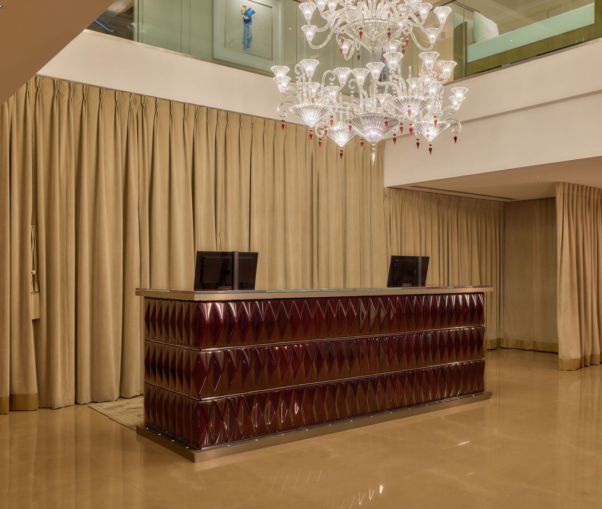 Concierge desk at The May Fair Hotel under a large chandelier.