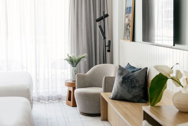 Atrium Twin at Elysium Manly featuring a cushioned lounge chair next to a wooden side table with plush pillows nearby