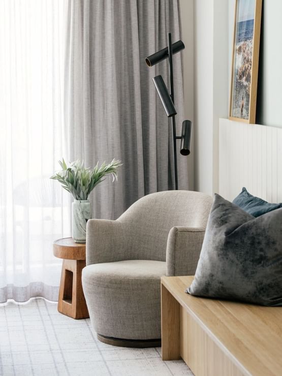 Sunset View Two Bedroom at Elysium Manly, featuring a armchair by a bench under a mounted TV near sheer curtains