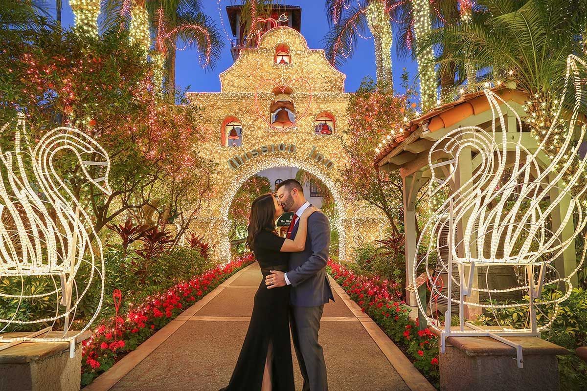 couple kissing at Mission Inn entrance decorated with christmas 