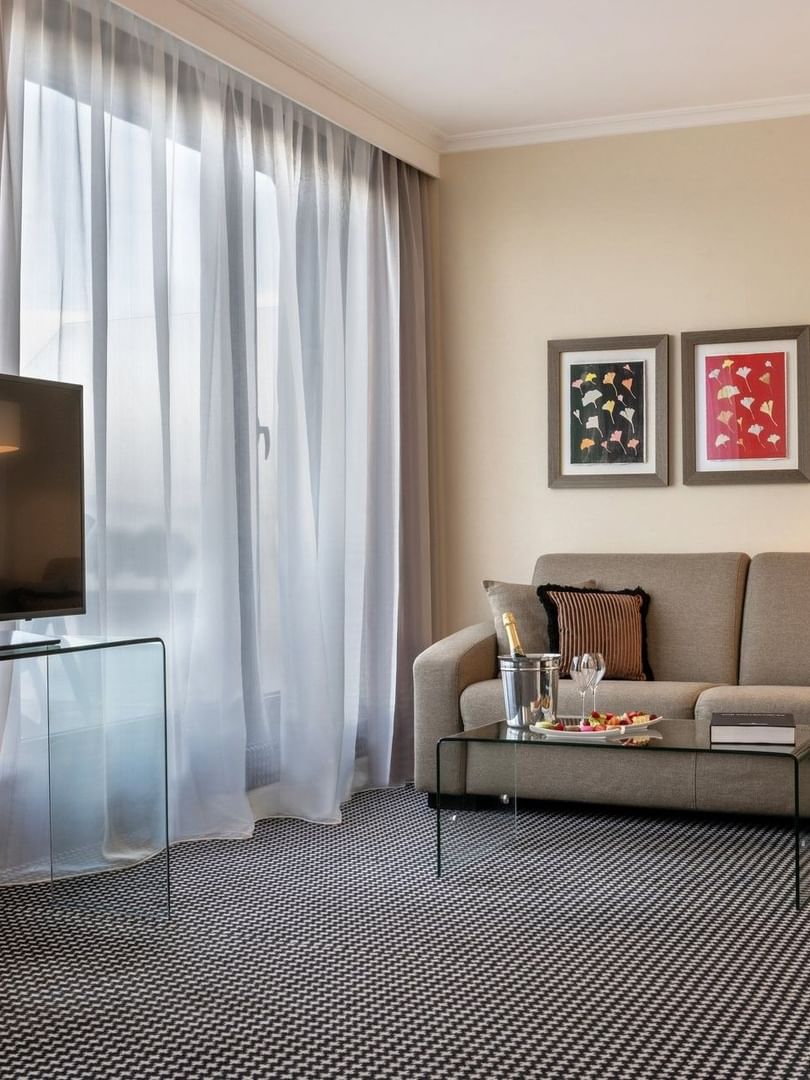 Salon avec canapé, table en verre et télévision dans la chambre « Penthouse Executive Terrace » de l'hôtel Warwick Geneva à Genève.