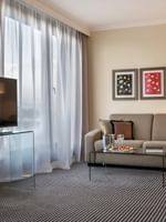 Salon avec canapé, table en verre et télévision dans la chambre « Penthouse Executive Terrace » de l'hôtel Warwick Geneva à Genève.