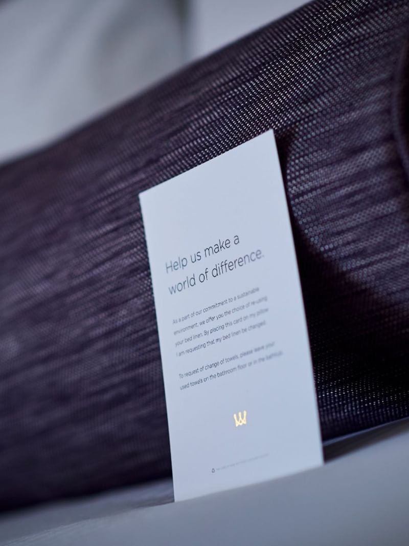 Sustainability card by a purple bolster pillow on a bed in Classic Rooms at Warwick Denver