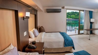 Dos camas con mesa de noche y balcón privado en la habitación de hotel Standard Ocean View en el hotel The Beach House de Panamá