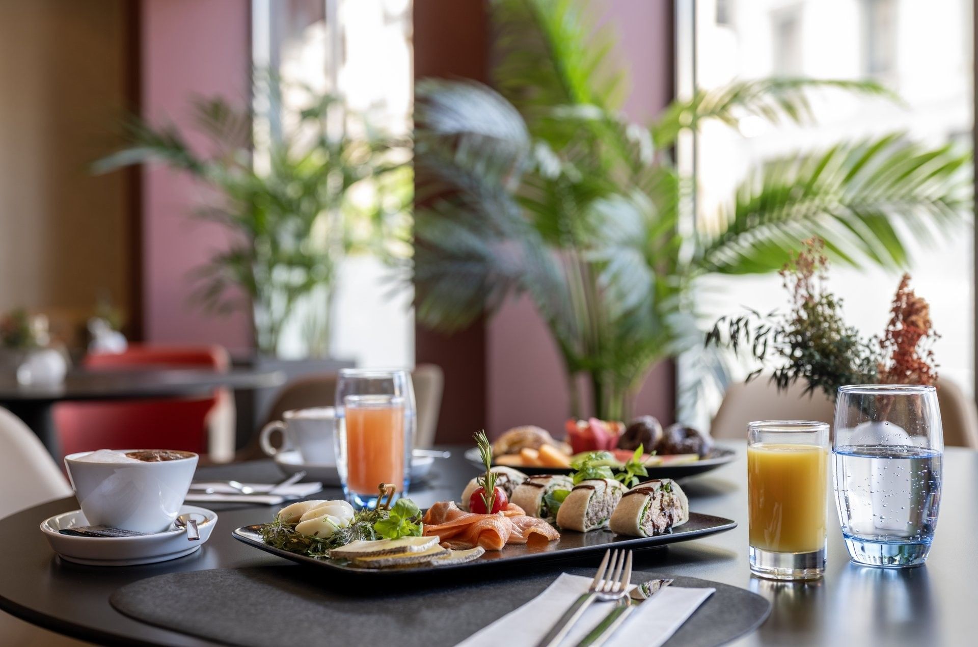 Breakfast table with smoked salmon, rolls, juices, and coffee, surrounding a dining area at Warwick Geneva