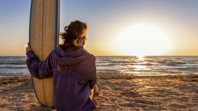 A lady holding her surfboard at the beach near Falmouth Tides