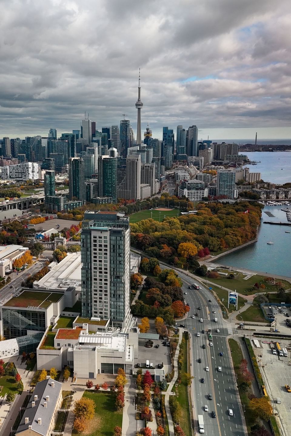 High aerial shot of modern high rise hotel building beside busy road and autumn trees near water at Hotel X Toronto