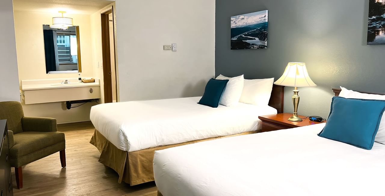 Hotel bedroom with two beds, paintings, chair, and mirror