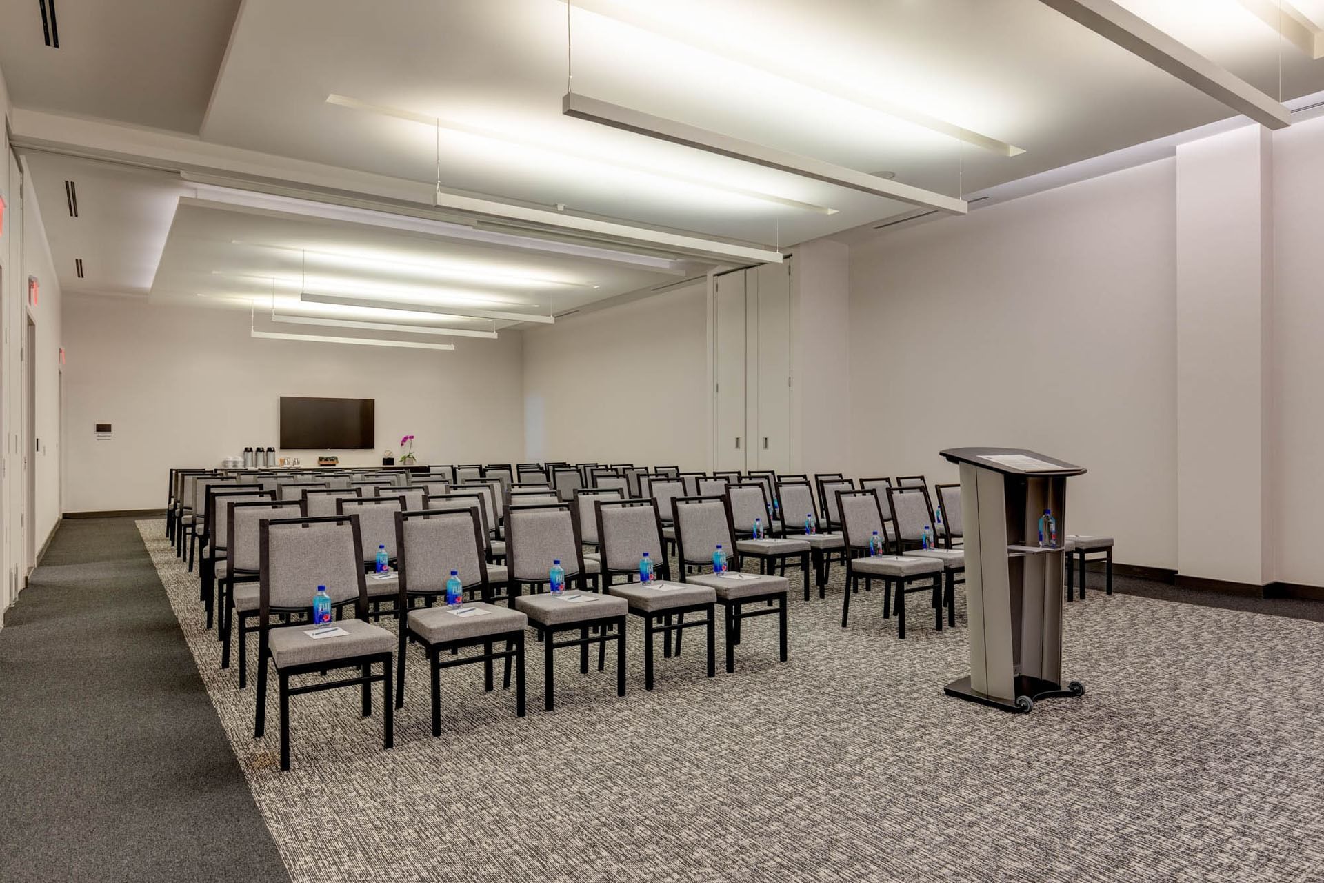 Long classroom setup tables with purple chairs facing a large projection screen inside Riverdale Park at Hotel X Toronto