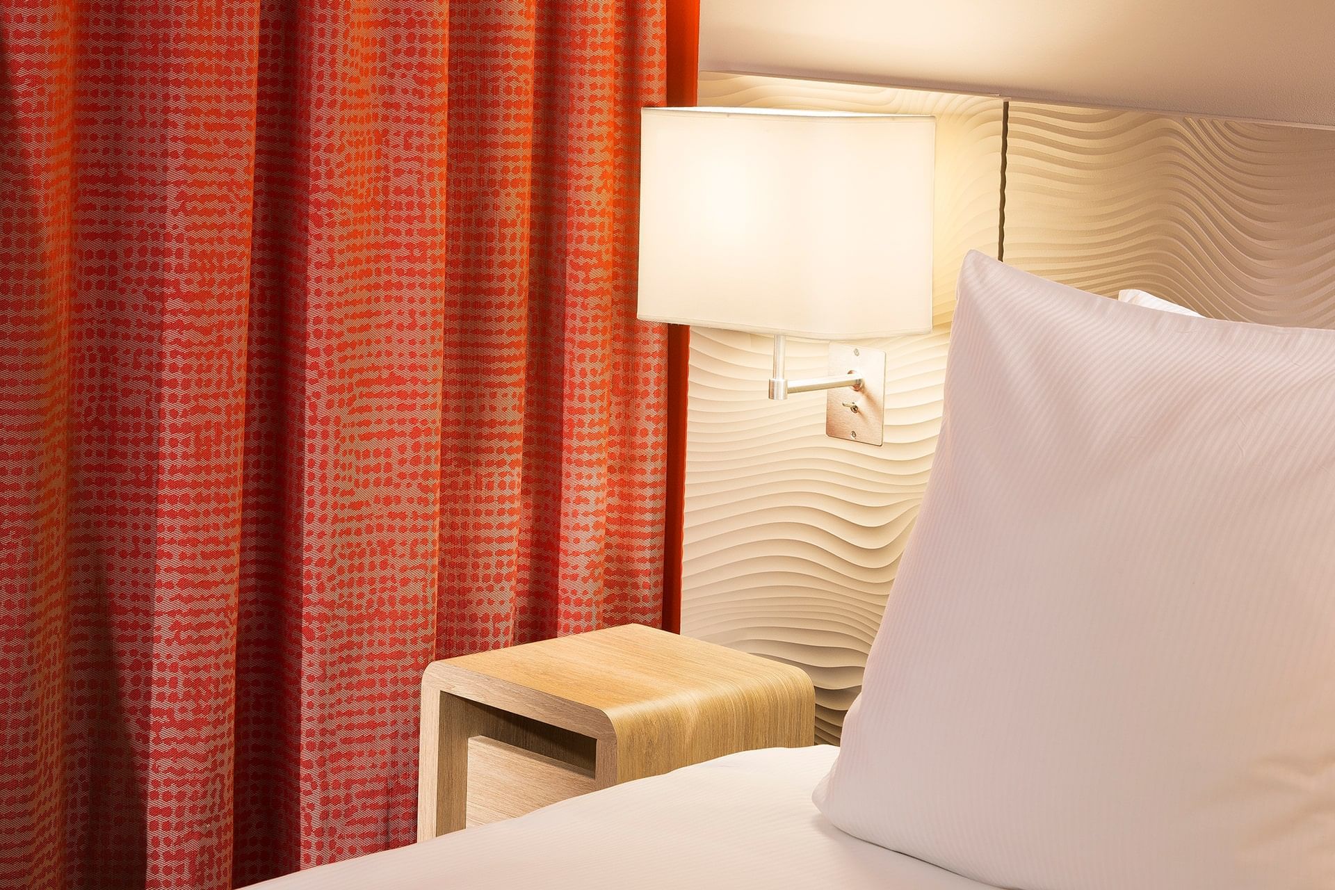 Lampe de chevet près du lit dans une chambre à Oceania Paris Roissy CDG