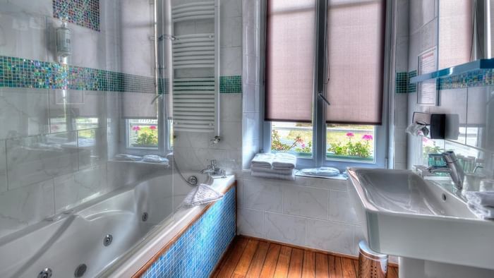 Salle de bains élégante avec baignoire et lavabo à l'Hôtel Villa Aultia.