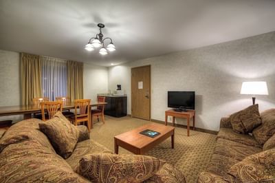 Modern Executive Suite living area at Moab Valley Inn with a comfy sofa, dining table, TV, and warm natural lighting