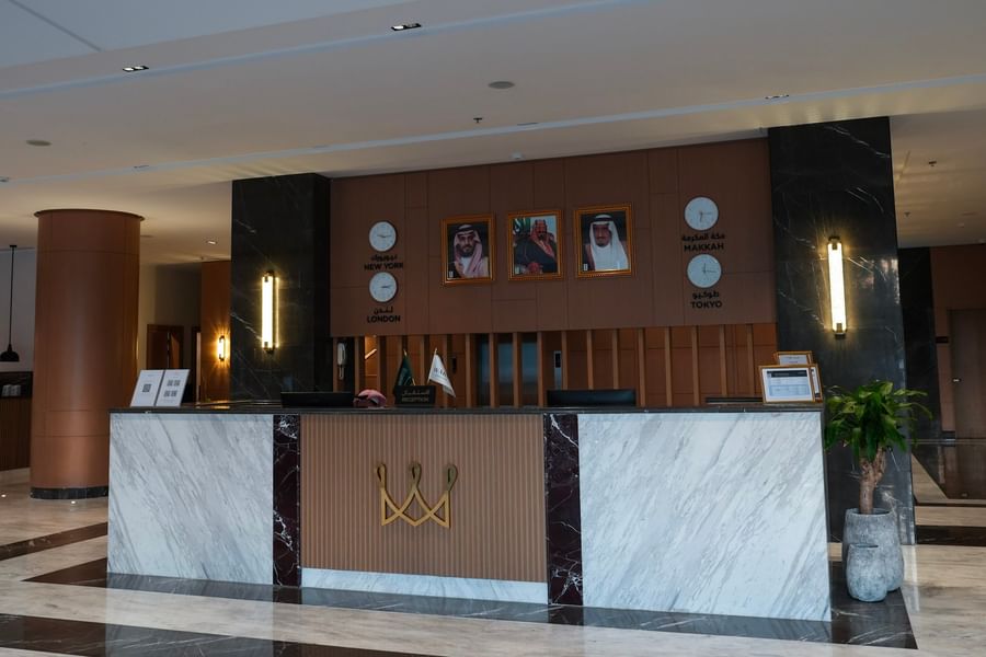 Modern hotel reception area with marble counter, framed pictures, and clocks at Warwick Hotel & Spa - Jeddah.