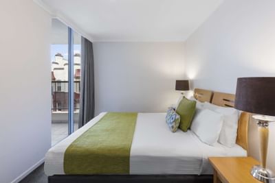 King bed & lamps in One Bedroom Apartment at Nesuto Hotels