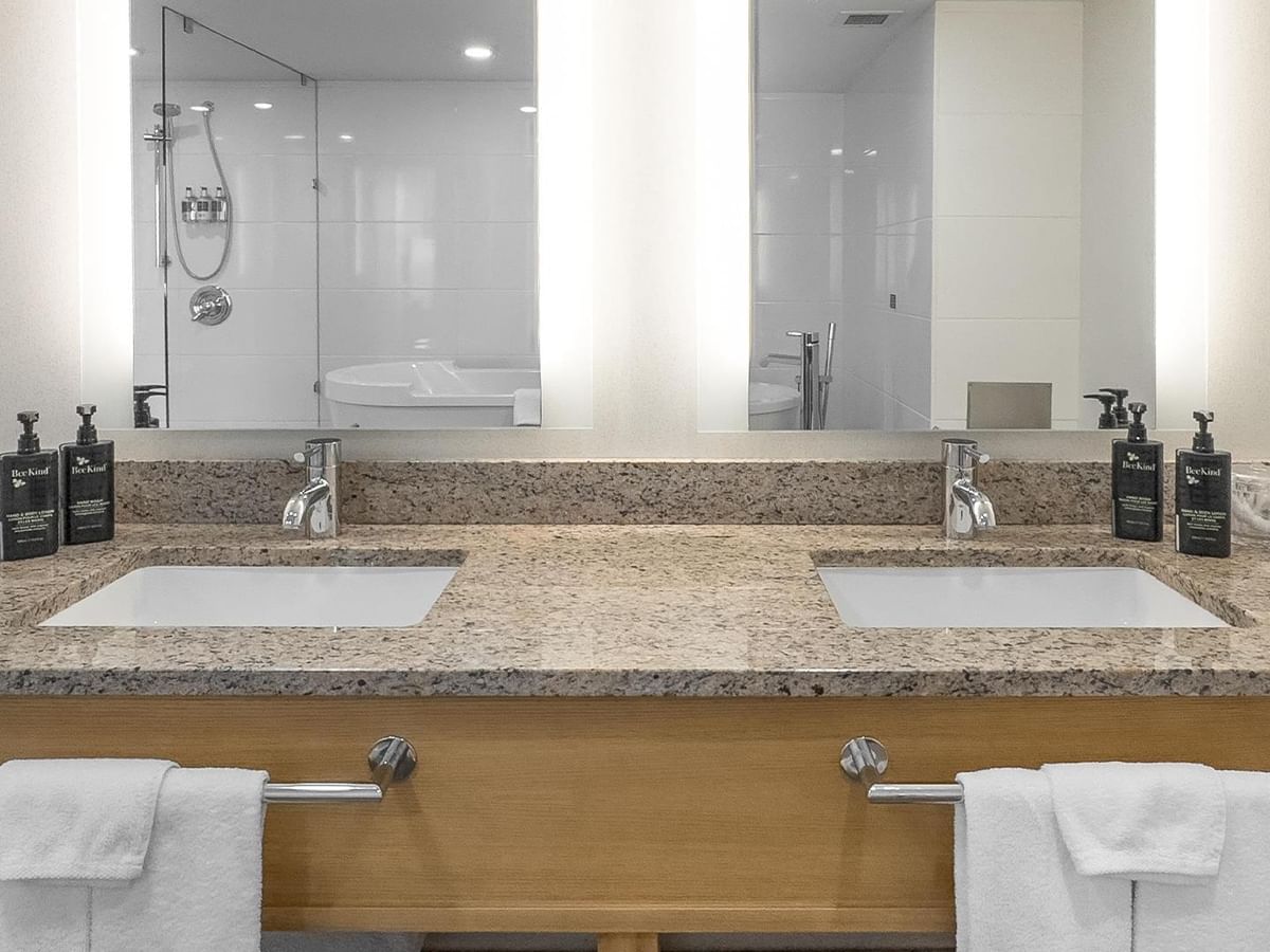Double vanity with granite countertops in a hotel bathroom.